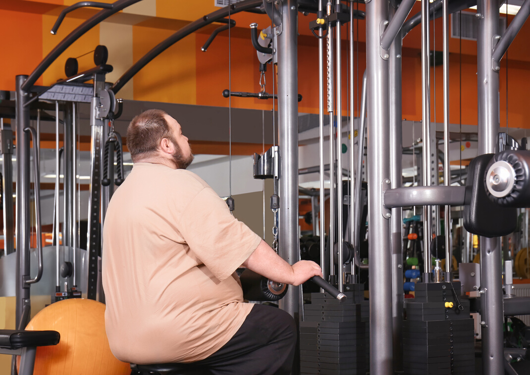 Plus Size Man Sitting on a Gym Machine 